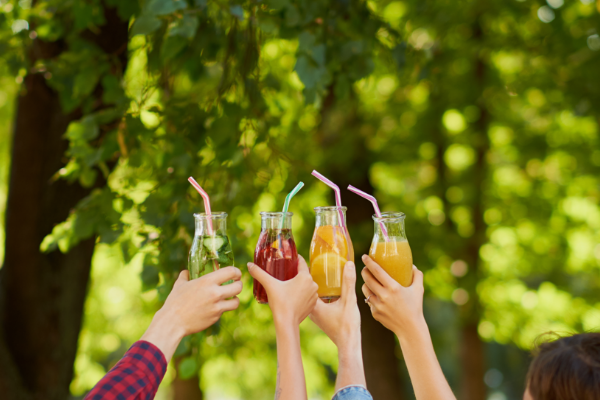 cuatro jóvenes brindan con zumos de frutas